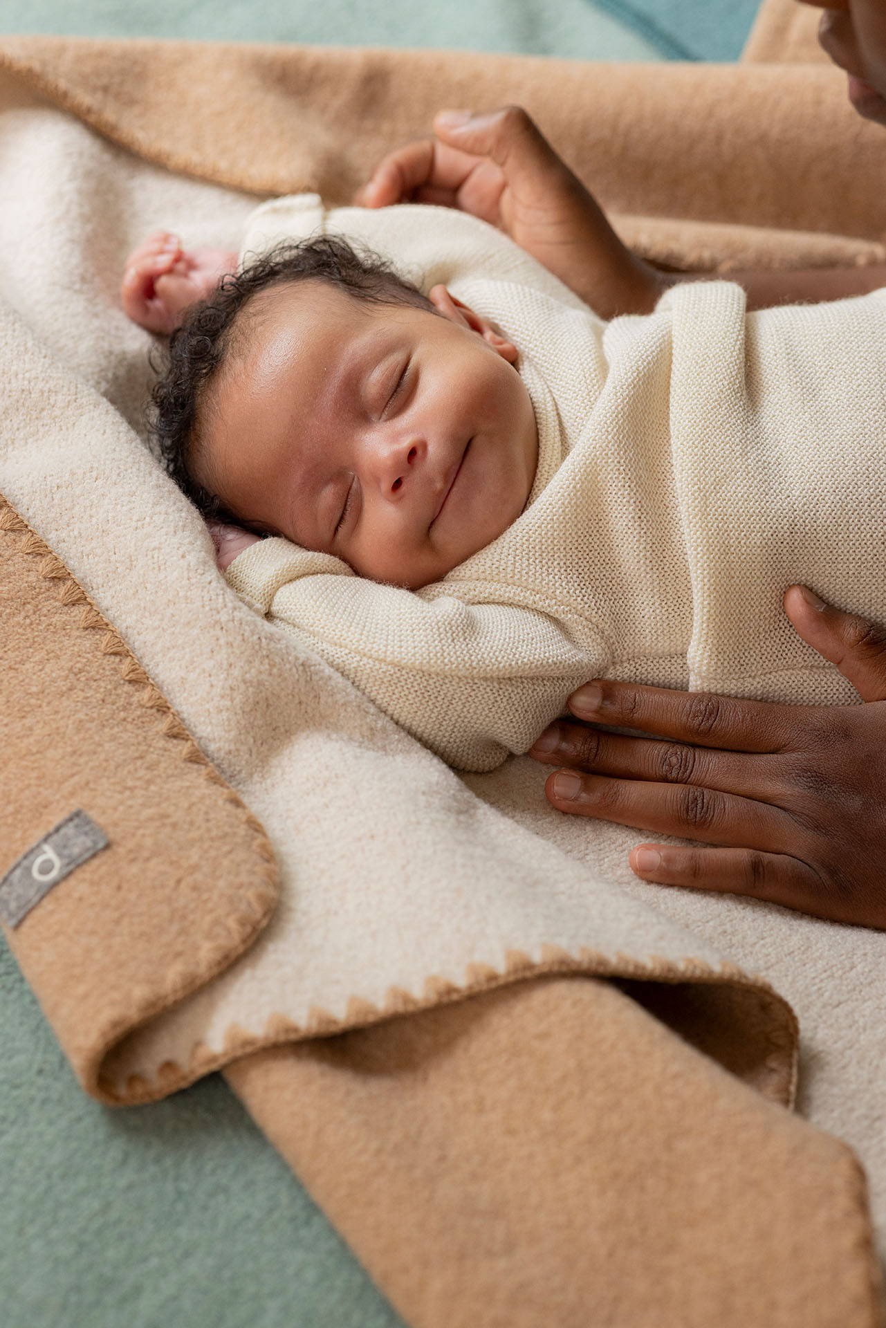 Baby mit hellbraunem Hautton im disana Baby-Pullover, Natur, auf Doubleface-Babydecke in Karamell-Natur schlafend