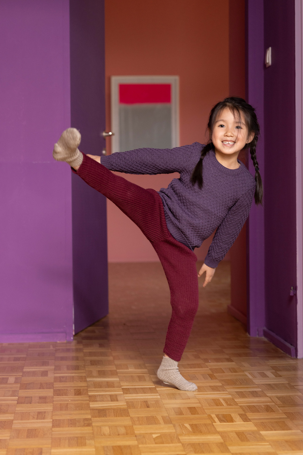 Asiatisches Mädchen in disana Aran-Pullover, Aubergine und Strick-Leggings Cassis aus bio-Merinowolle bei einer Ballettübung